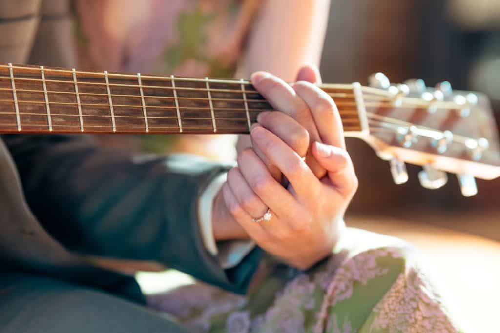 Husband and wife playing acoustic guitar at wedding ceremony
